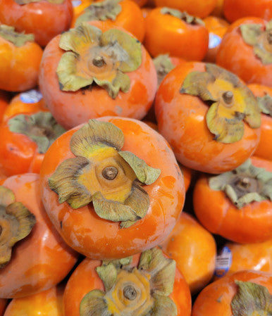 Close-up of orange persimmons with textured, greenish calyx areas.